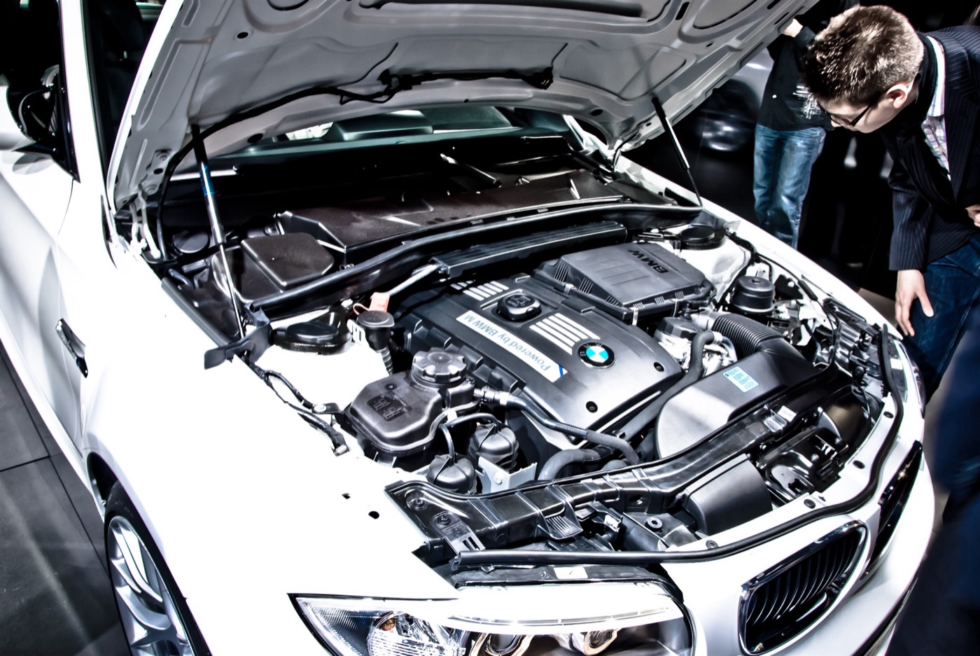 Open bonnet of a white BMW 1M showing the N54 engine cover marked Powered by BMW M